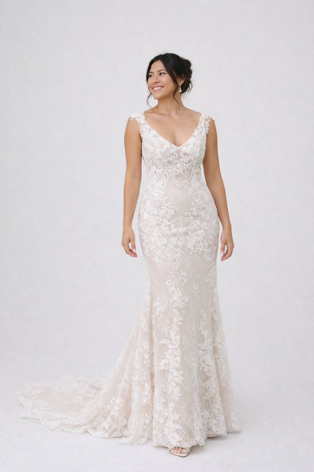 Woman wearing a white lace wedding dress on a white background