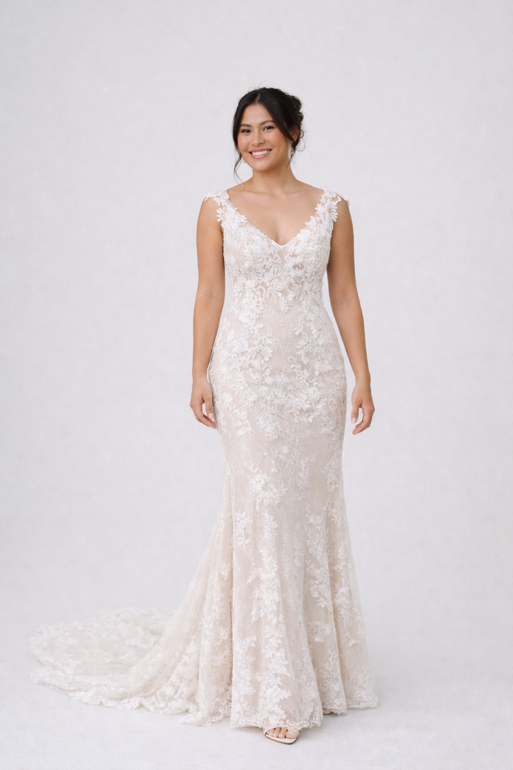 Woman wearing a white lace wedding dress on a plain background